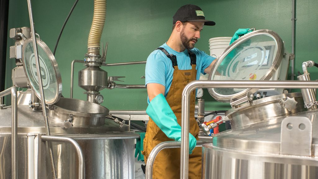 A brewery worker inspecting equipment in a craft brewing facility.